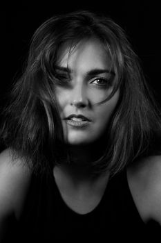 Elegant black and white portrait of a woman with expressive eyes captured in a studio setting.