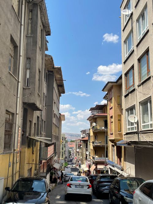 Free Lively view of a narrow urban street lined with historic buildings under a clear blue sky. Stock Photo