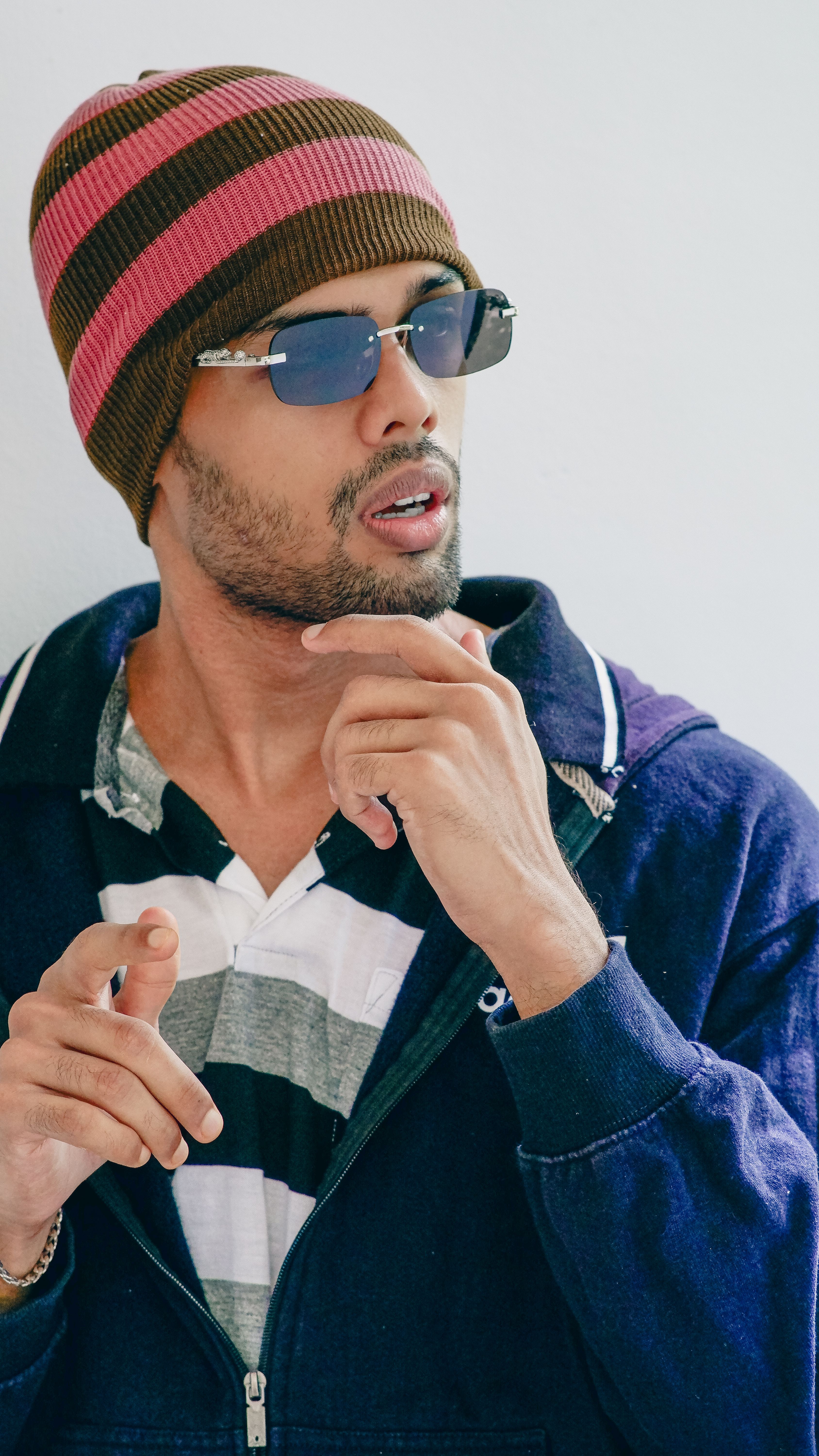 Casual portrait of a fashionable man wearing shades and a beanie indoors.