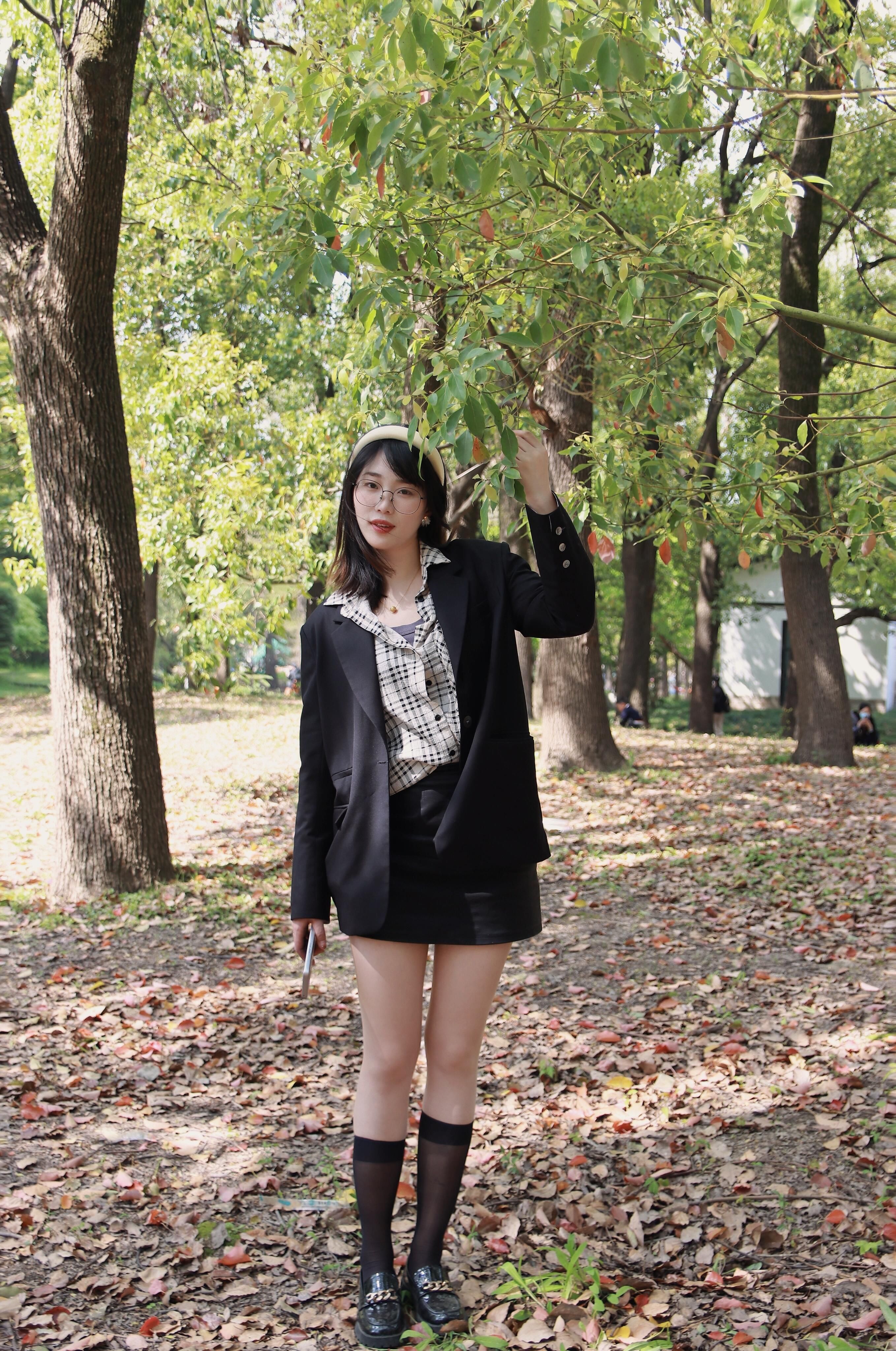 Young woman in chic attire enjoys a sunny day in a Nanjing park.