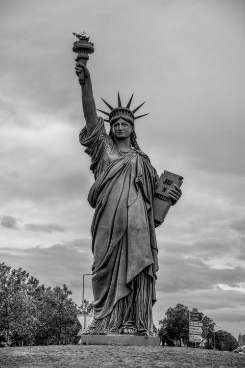 Free Black and white image of a Statue of Liberty replica in Colmar, France, with cloudy skies. Stock Photo