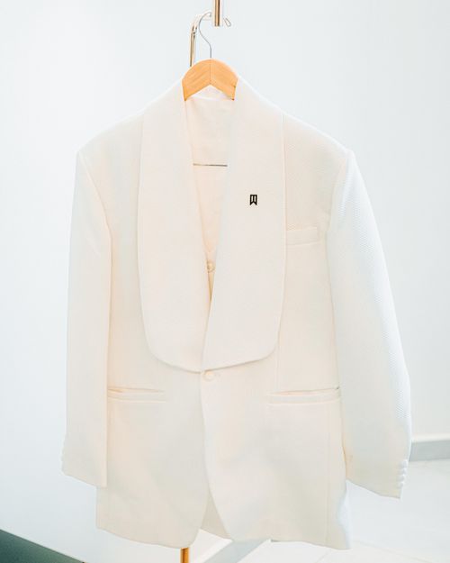 Free A stylish white tuxedo hung elegantly against a bright backdrop, perfect for formal occasions. Stock Photo