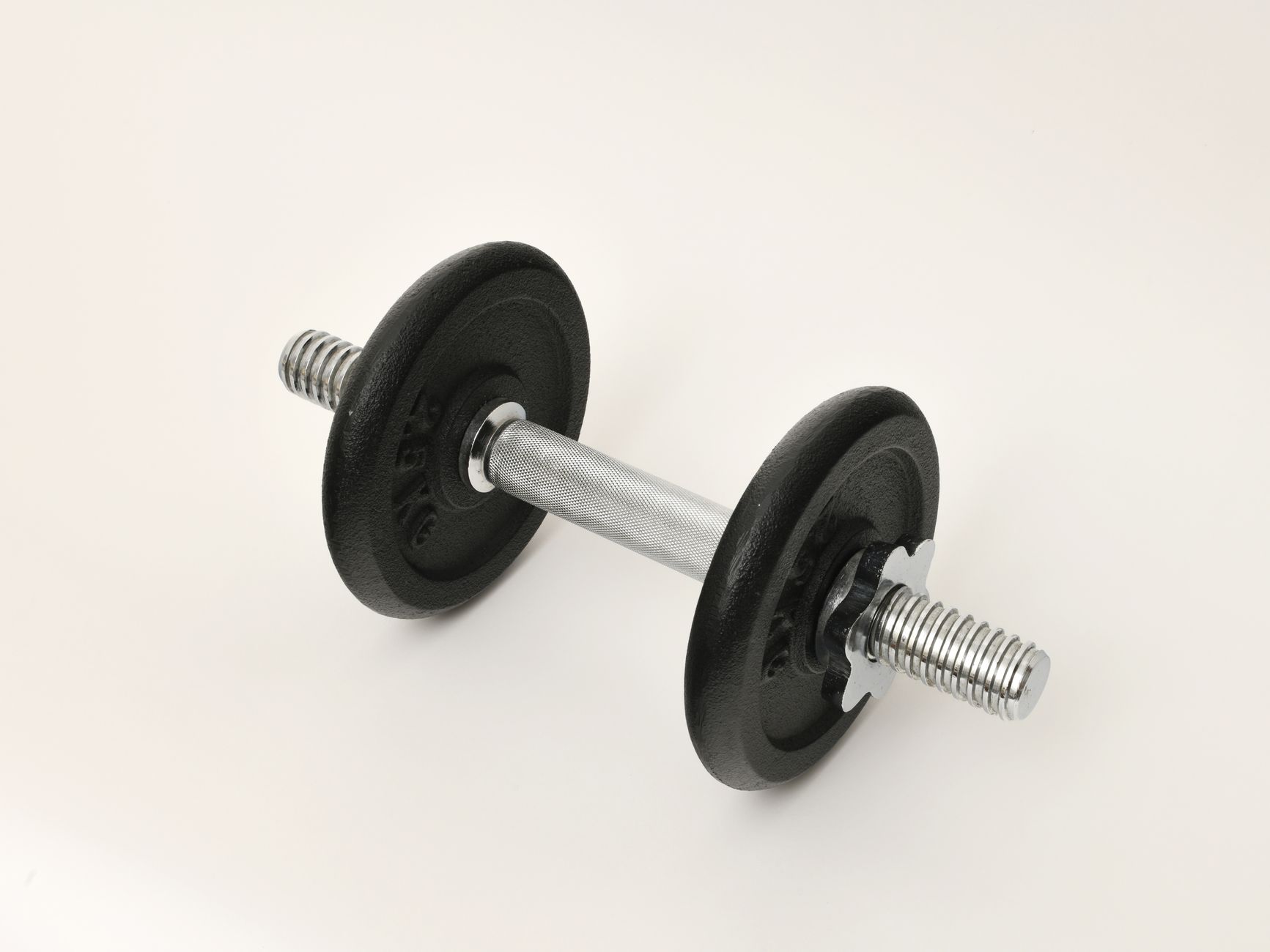 A black iron dumbbell on a white background, ideal for gym and fitness concepts.