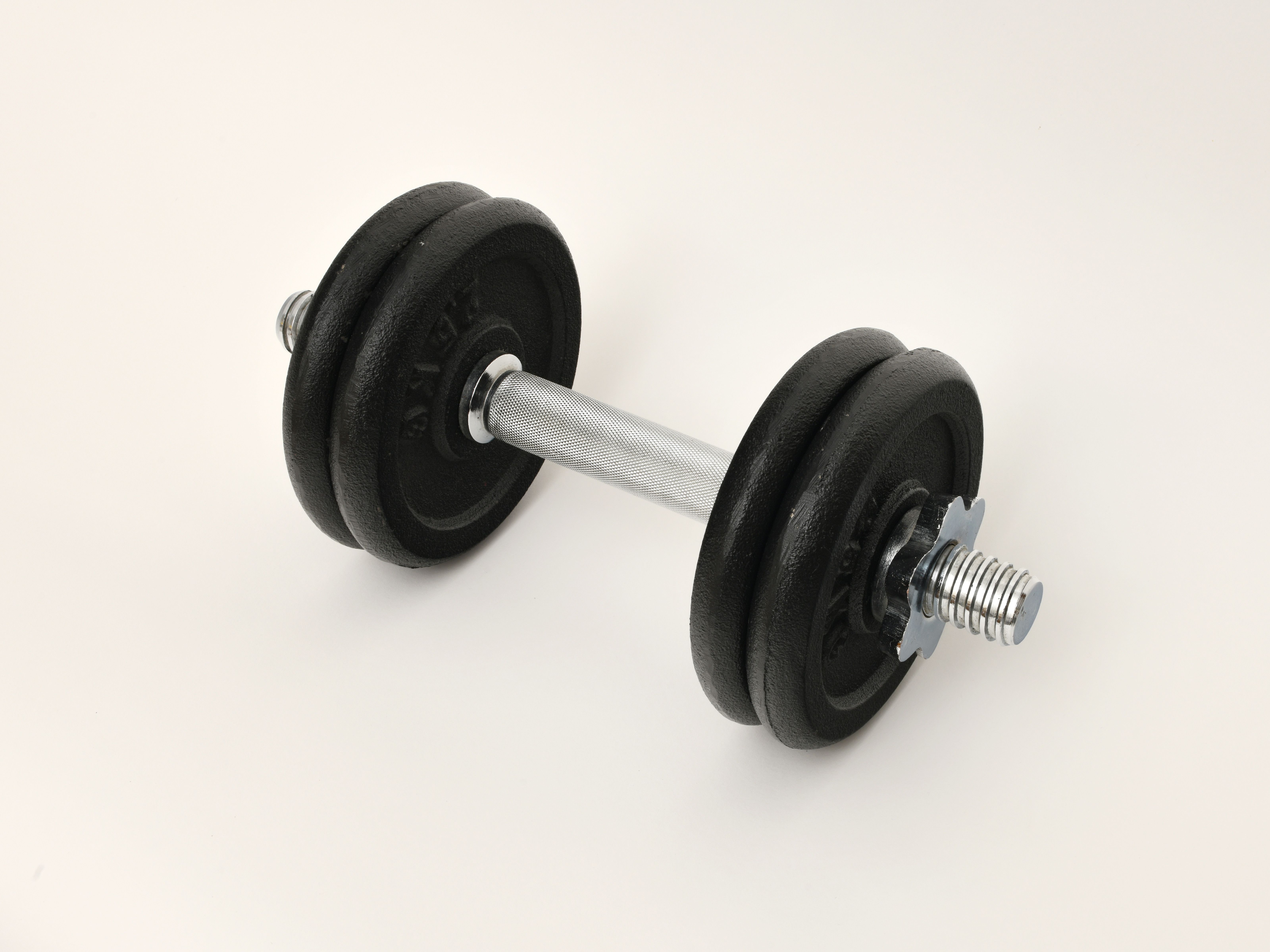 Close-up of a black dumbbell isolated on a white background, perfect for fitness themes.