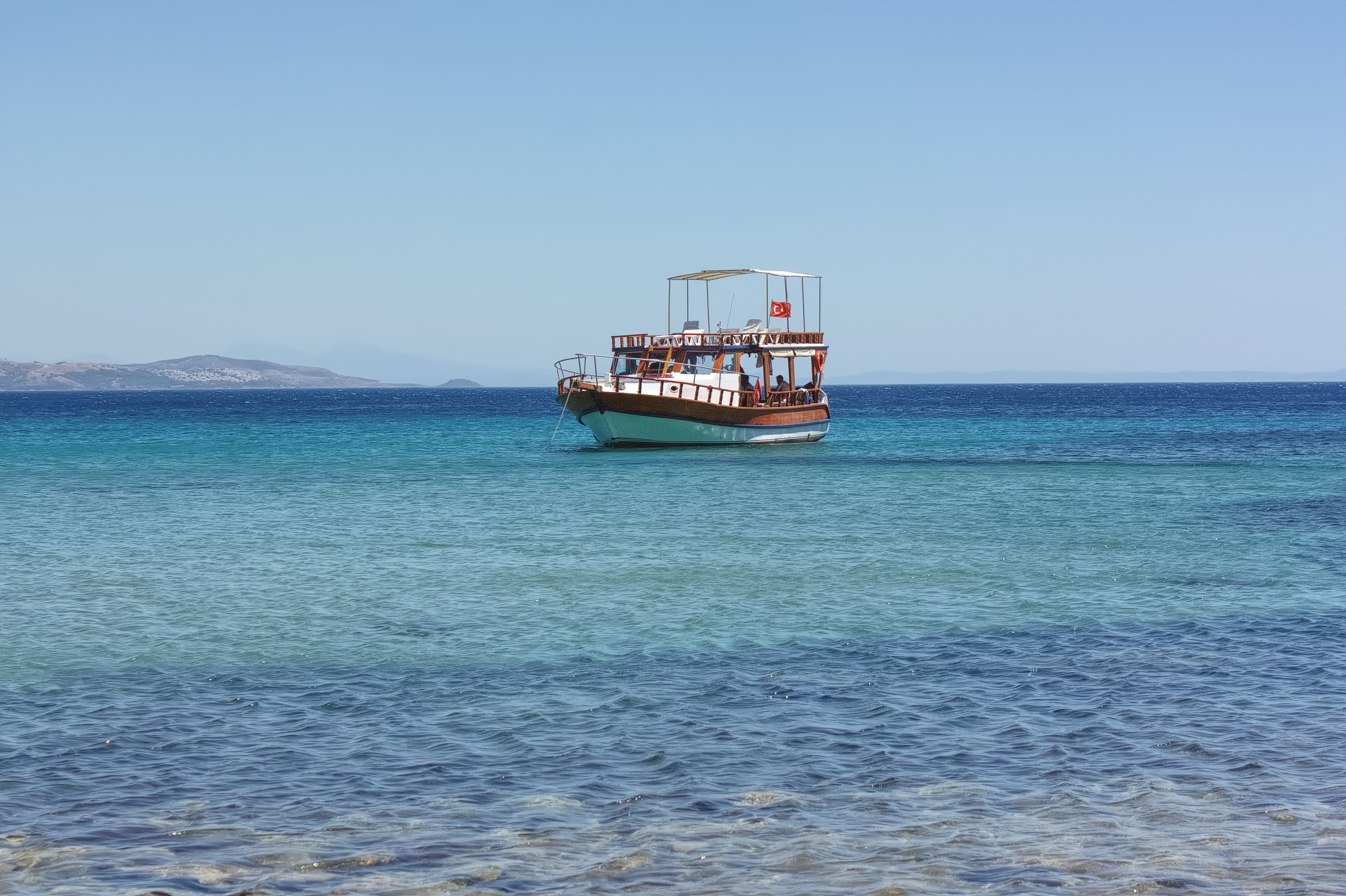 A scenic view of a traditional Turkish boat on the turquoise waters of Sığacık, İzmir.