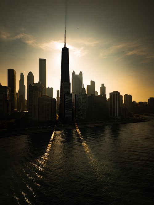 Free Striking silhouette of Chicago skyline at sunset with sun rays reflecting on Lake Michigan. Stock Photo