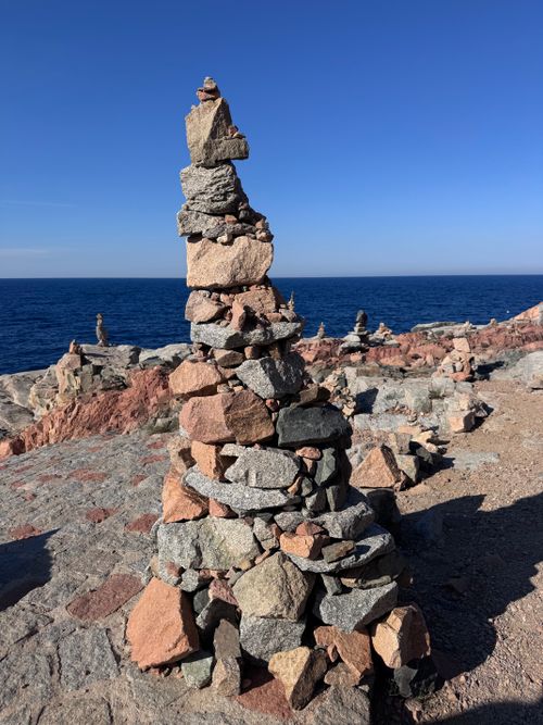 Free A stunning cairn of stacked stones stands against the coastal backdrop of Sardinia's blue Mediterranean Sea. Stock Photo