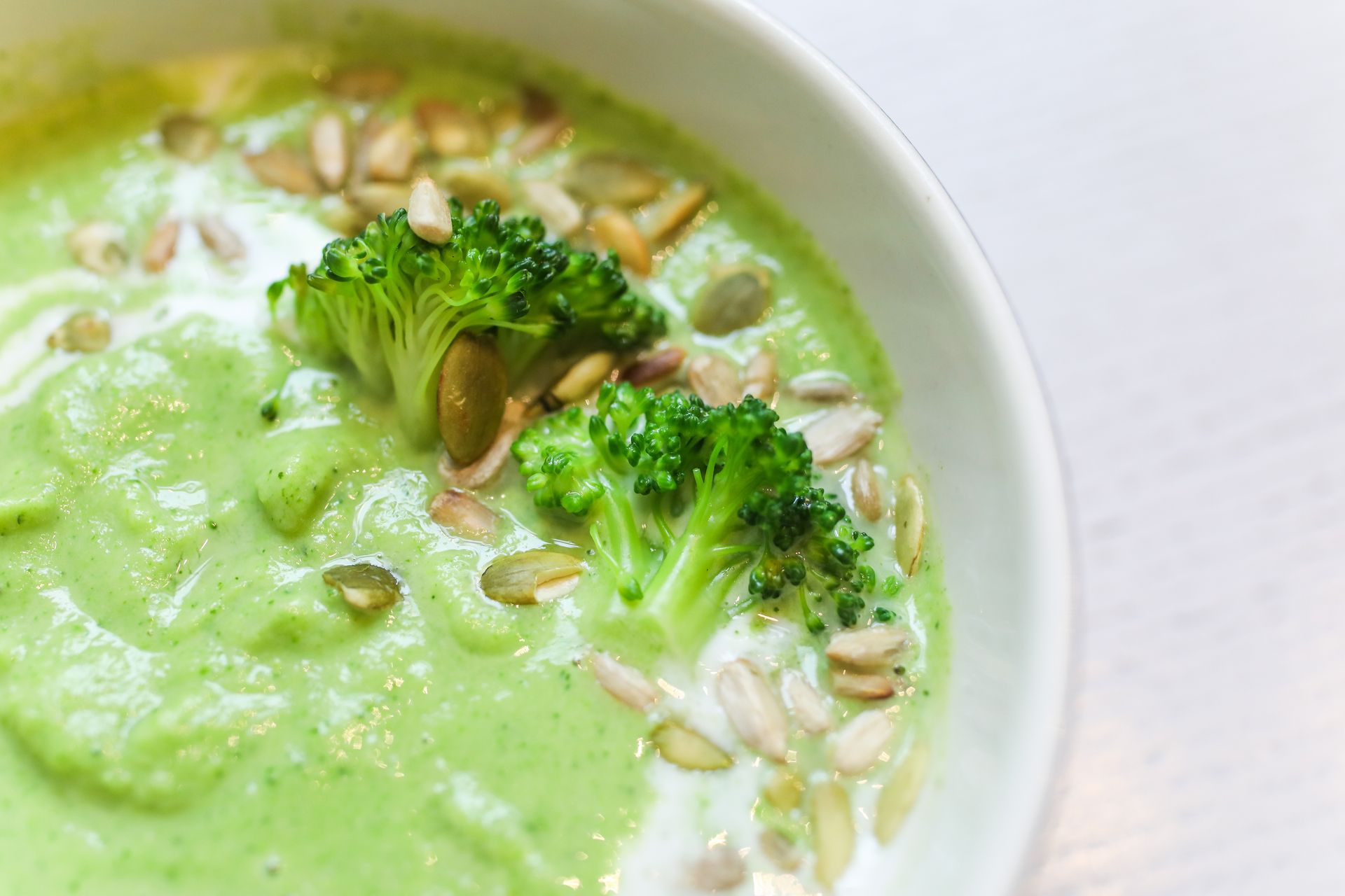 Delicious and creamy green broccoli soup topped with seeds for a healthy meal.