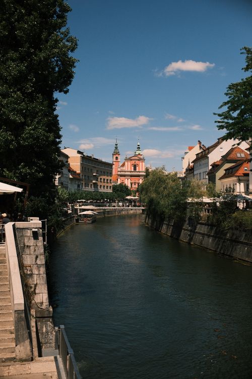 Free A picturesque view of Ljubljana canal with historic architecture under a clear sky. Stock Photo