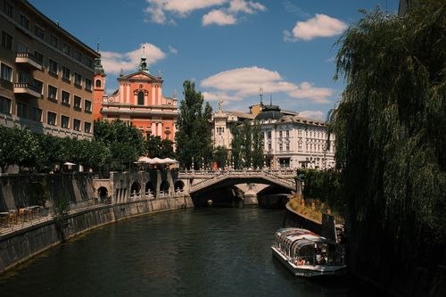 Free A scenic view of Ljubljana's famous Triple Bridge with a passing boat. Stock Photo