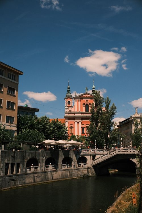 Free Scenic view of Ljubljana with the iconic Franciscan Church by the river under a clear blue sky. Stock Photo