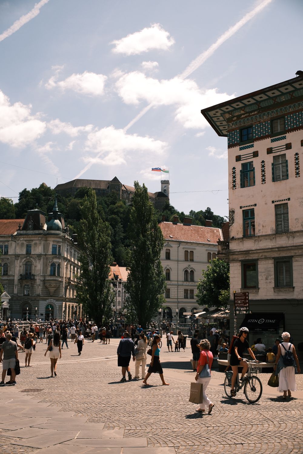 Piață animată din Ljubljana, cu castelul vizibil în fundal