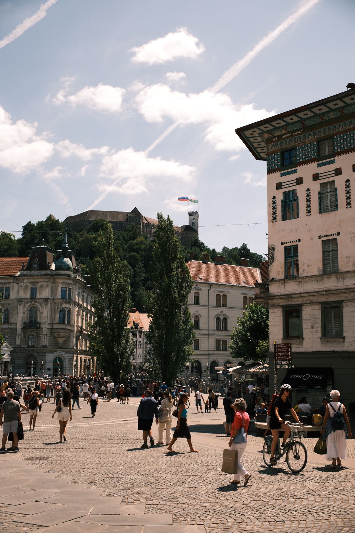 A busy square in Ljubljana with the castle visible above