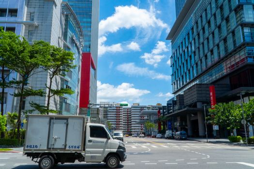 A bustling street scene in Taipei with modern architecture and a delivery truck.