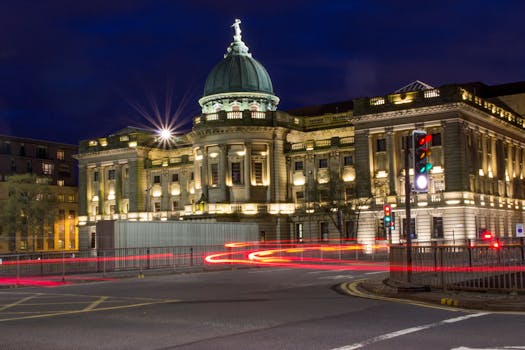 The Mitchell Library brightly lit with traffic light streaks in Glasgow, Scotland at night.