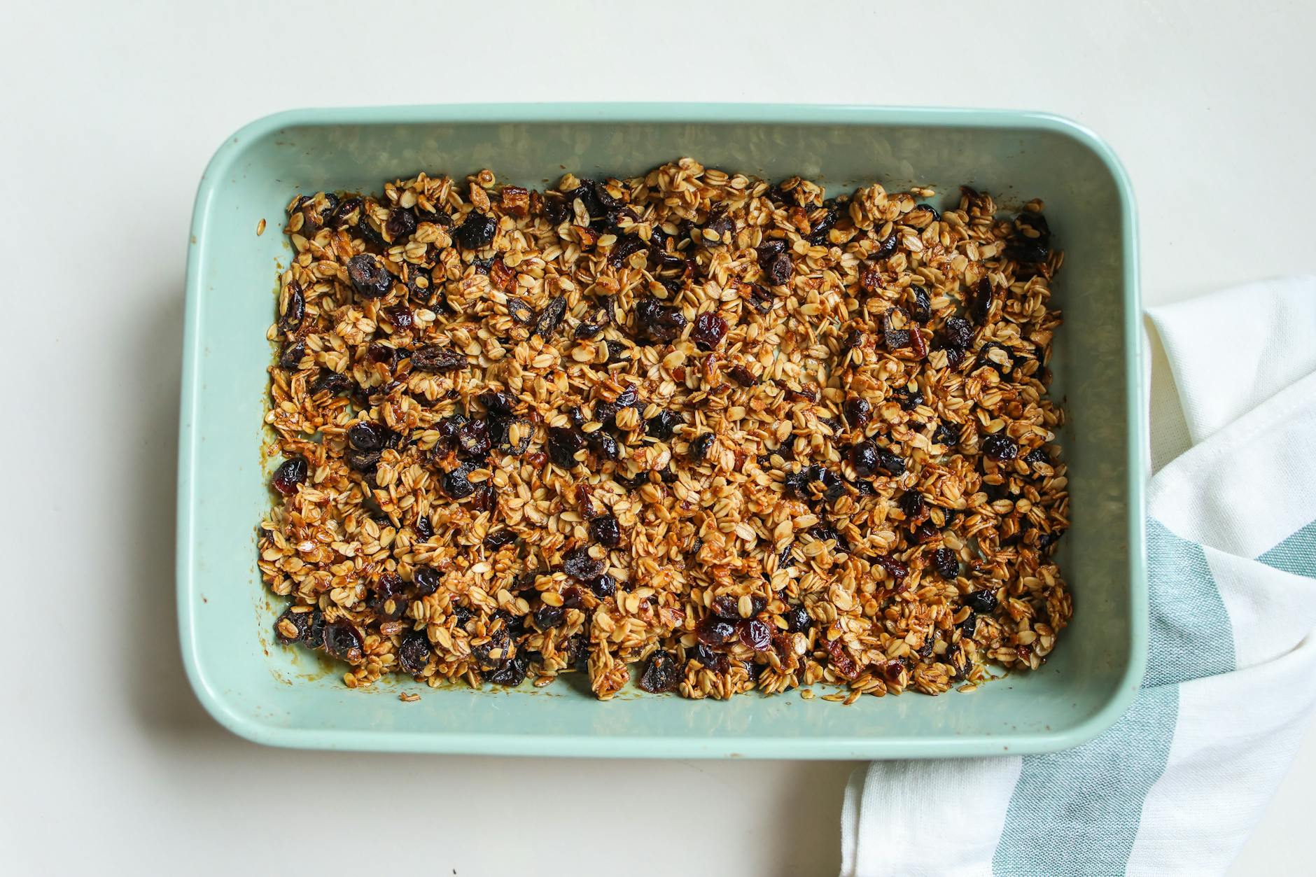 Freshly baked granola with oats and raisins in a blue baking dish for a healthy breakfast.