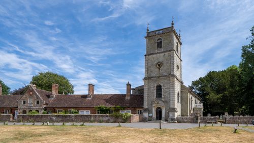 Free A picturesque view of a historic church and almshouses under a blue sky. Stock Photo