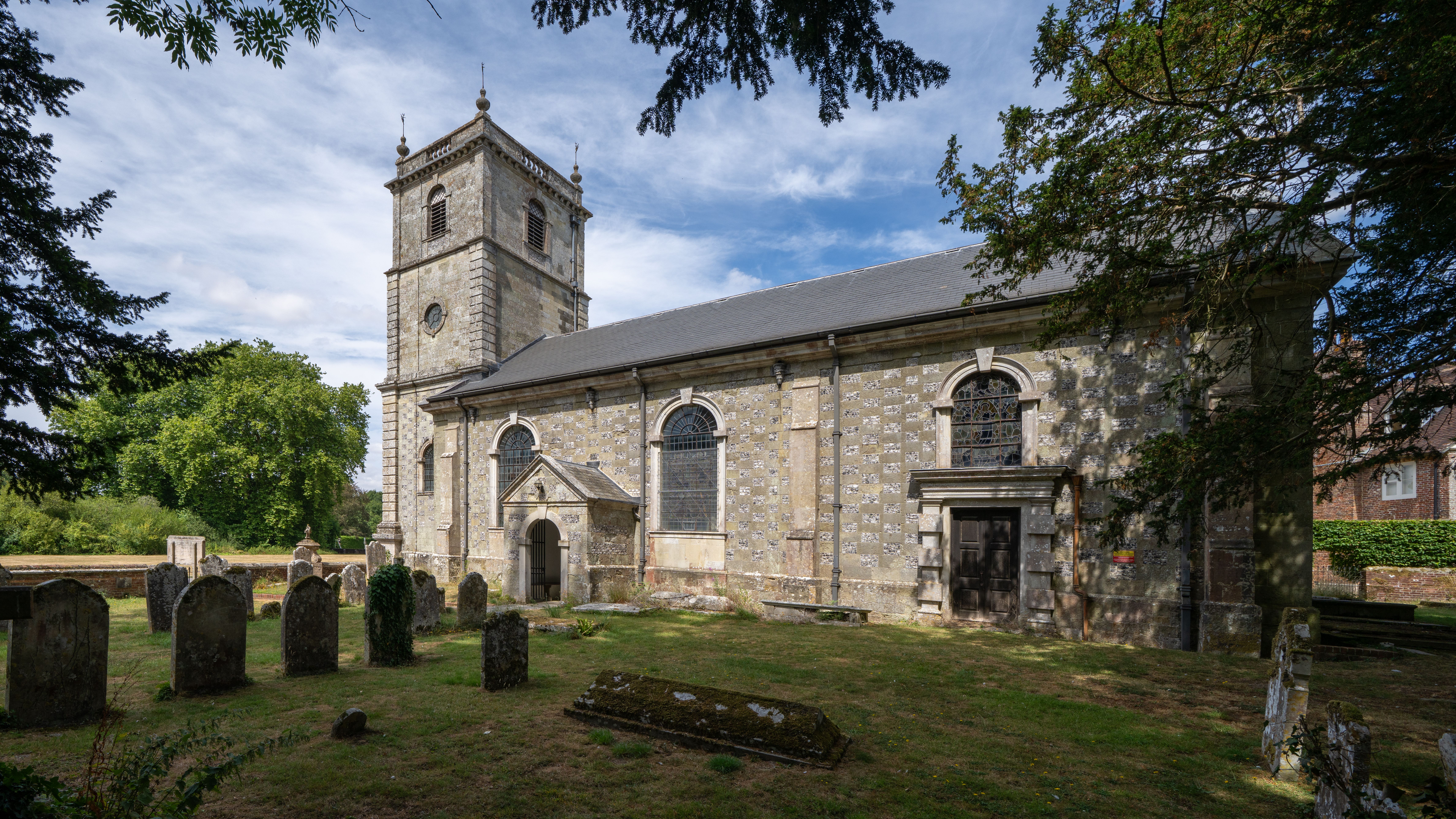 Beautiful historic church with cemetery in Wimborne Saint Giles, England, under blue sky.