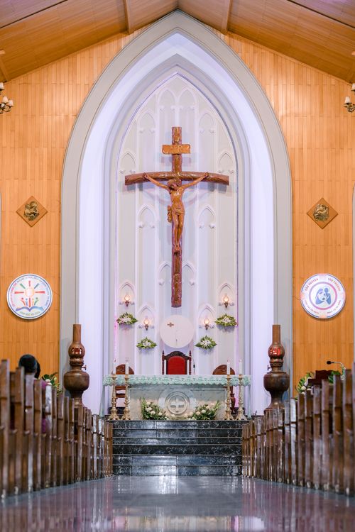 Free Solemn church interior featuring a wooden cross and altar with floral decorations. Stock Photo