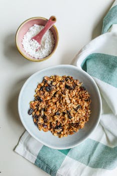 一碗自制的格兰诺拉麦片，上面撒着葡萄干和椰子片，非常适合作为营养早餐