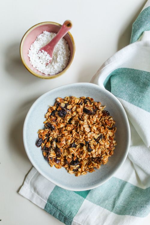 Free Top view of a bowl of homemade granola with raisins and a side of coconut flakes, perfect for a nutritious breakfast. Stock Photo