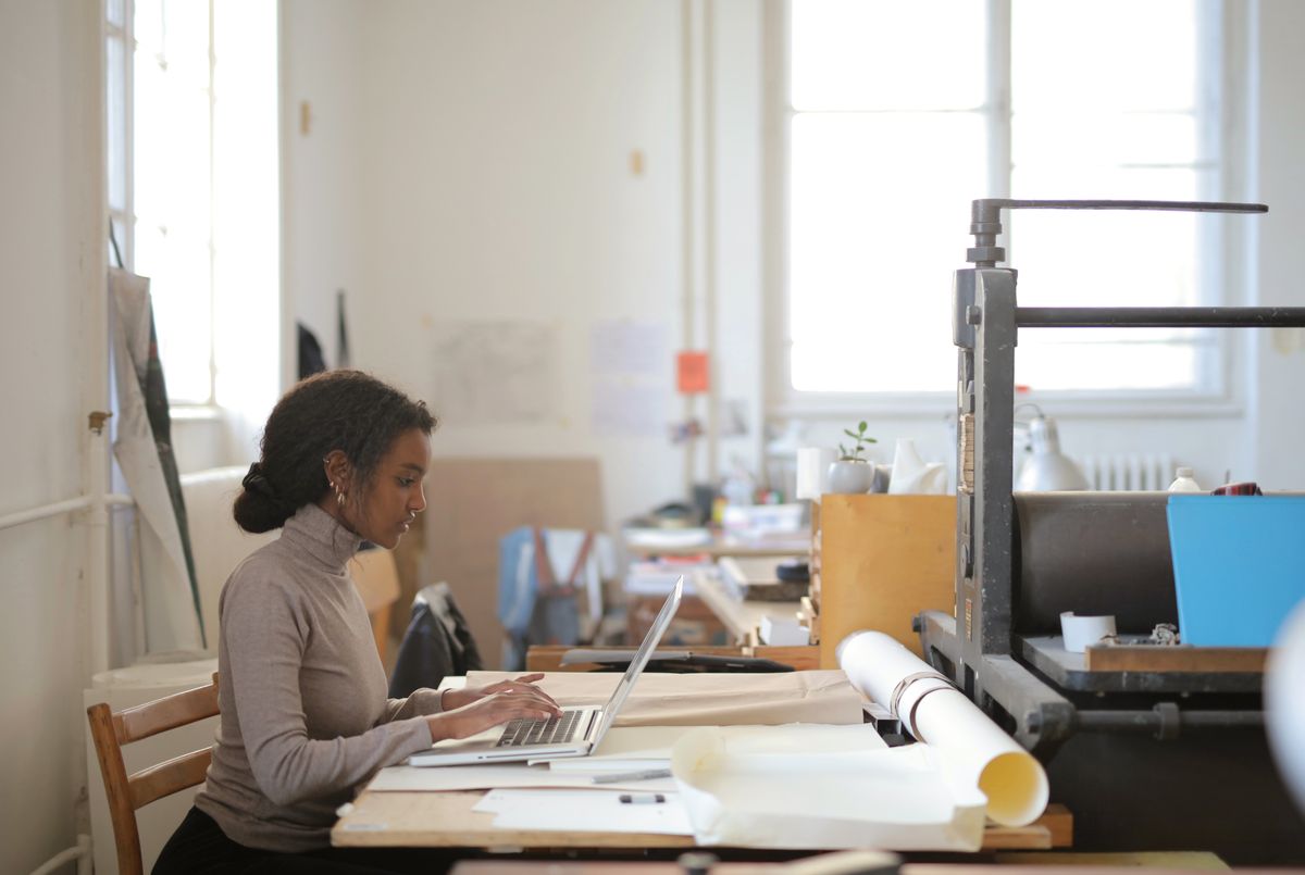 Writer working at a laptop in a sunlit print studio — Andrea Piacquadio on Pexels