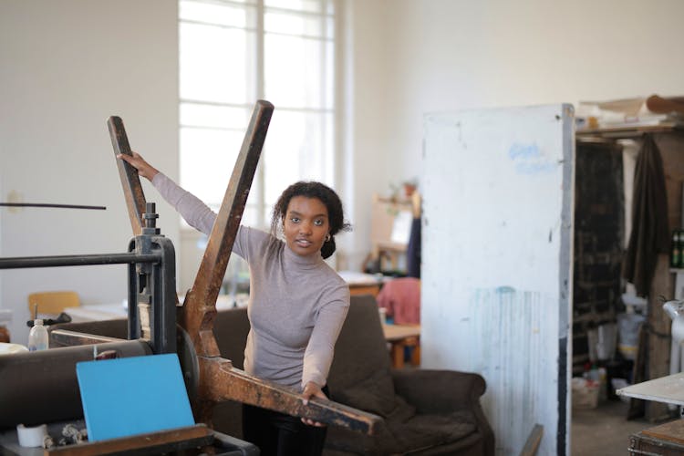 Young African American Artisan Moving Wheel Of Paper Rolling Machine