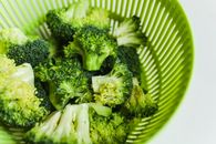 将切好的新鲜西兰花放入绿色漏勺，以凸显其鲜艳的色彩和新鲜感