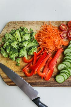 Sliced vegetables and knife on a wooden board, perfect for healthy meal preparation.