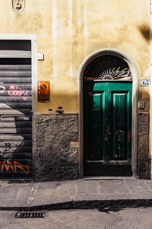 Free Rustic green door with arched top in Florence, capturing Italian street charm and history. Stock Photo