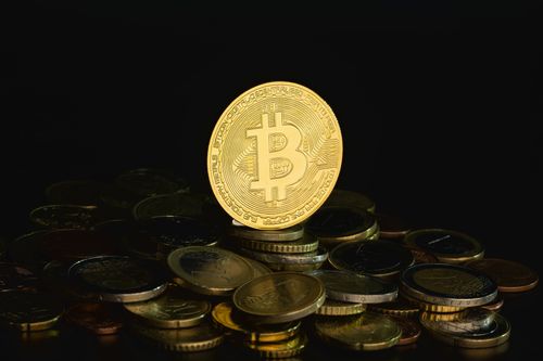Free Gold Bitcoin on a stack of coins against a dark background, symbolizing wealth and decentralization. Stock Photo