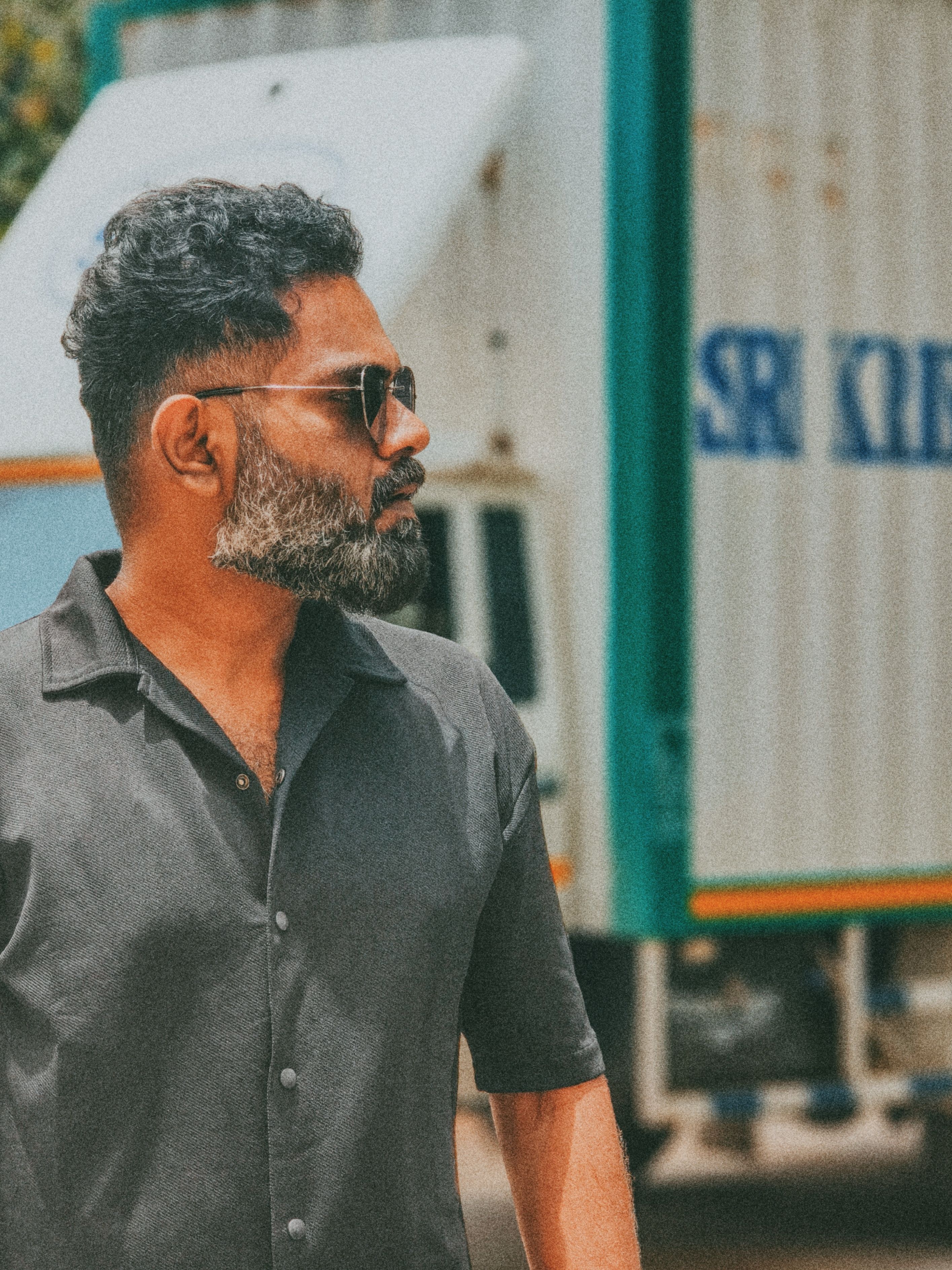 A fashionable man with sunglasses posing next to a truck outdoors.