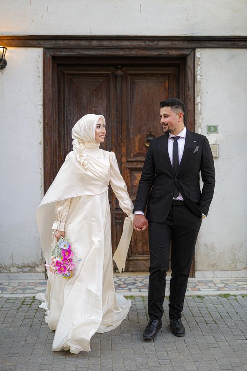 Free Happy couple in formal attire holding hands during an outdoor wedding photoshoot. Stock Photo