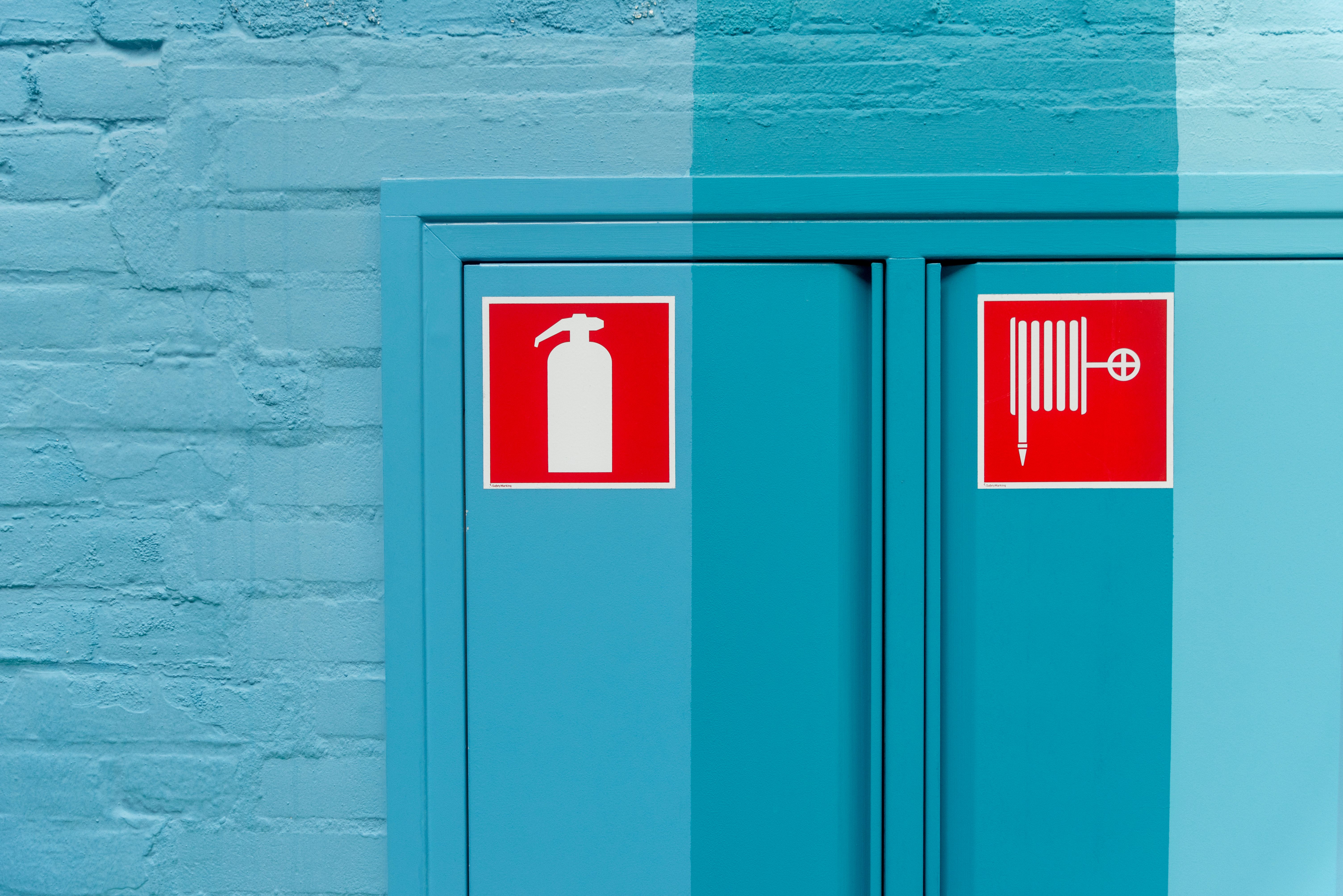 Blue wall featuring prominent fire extinguisher and hose signs for safety.