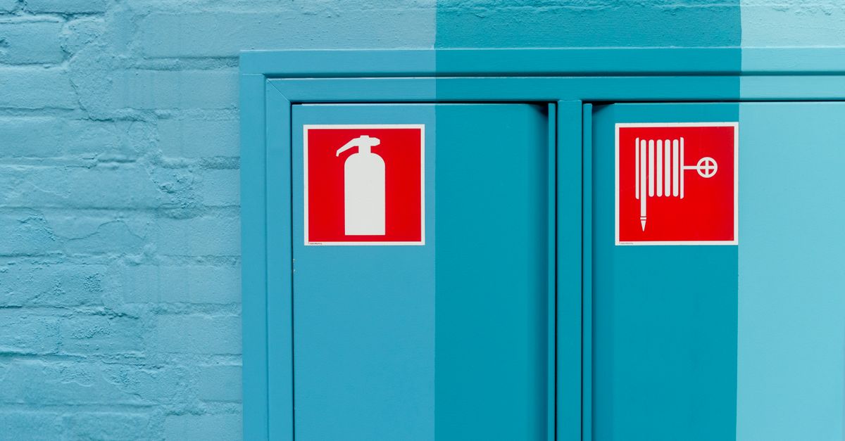 Blue wall featuring prominent fire extinguisher and hose signs for safety.