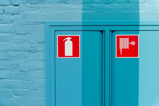 Blue wall featuring prominent fire extinguisher and hose signs for safety.
