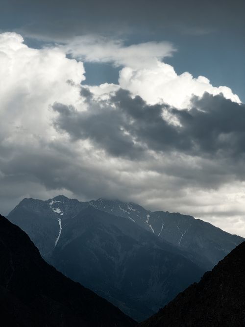 Free Majestic mountain peaks under a dramatic cloudy sky, captured in a serene setting. Stock Photo