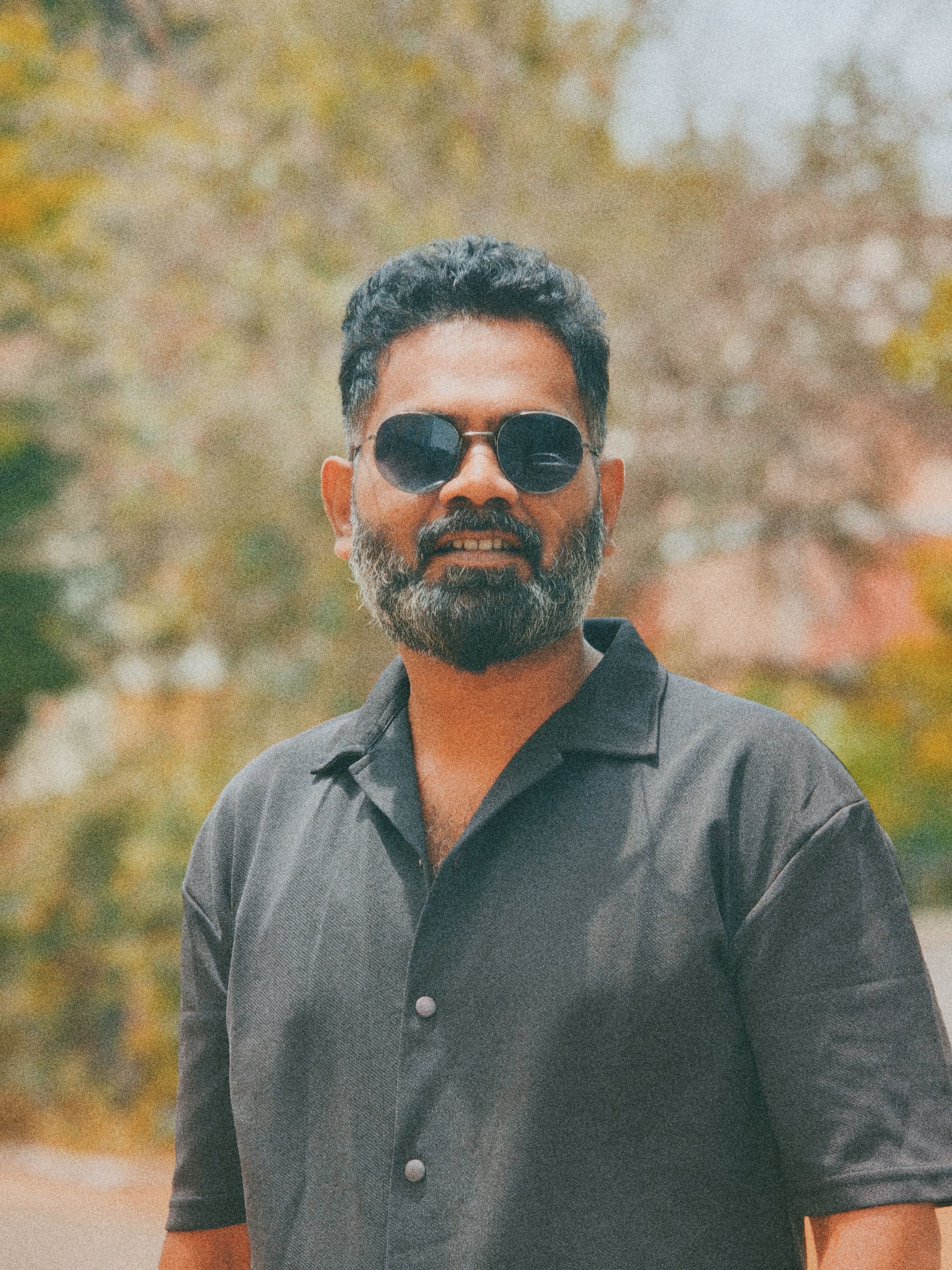 Portrait of a smiling man with sunglasses enjoying a sunny day outdoors in Coimbatore, India.