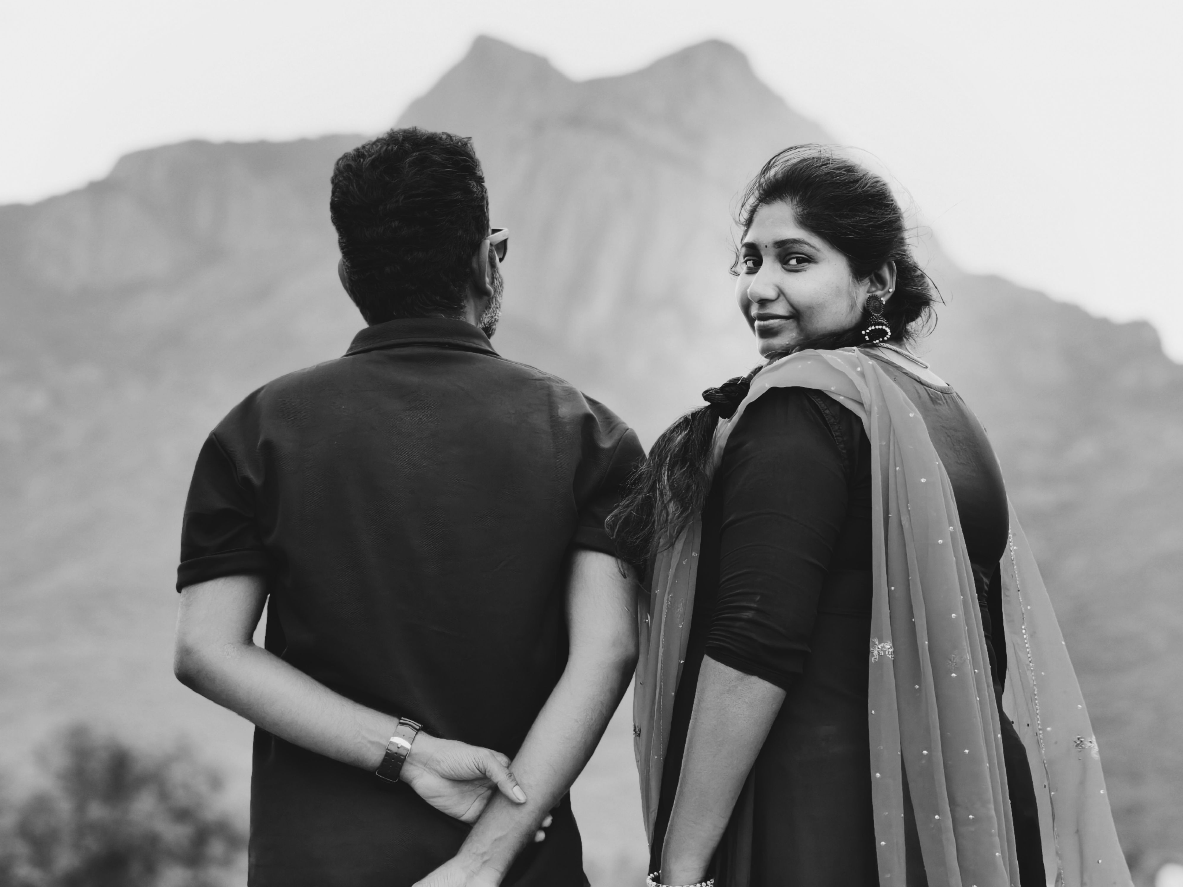 A couple enjoys a serene mountain view in Coimbatore, India, captured in black and white.