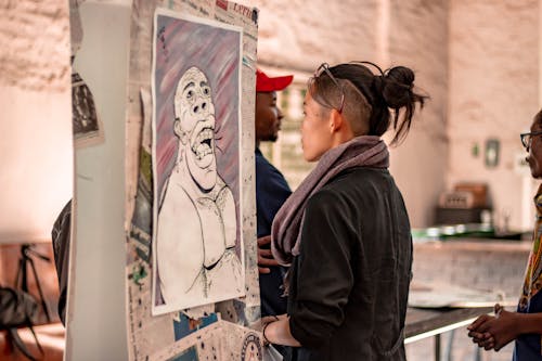 Ethnic woman observing creative portrait on exhibition
