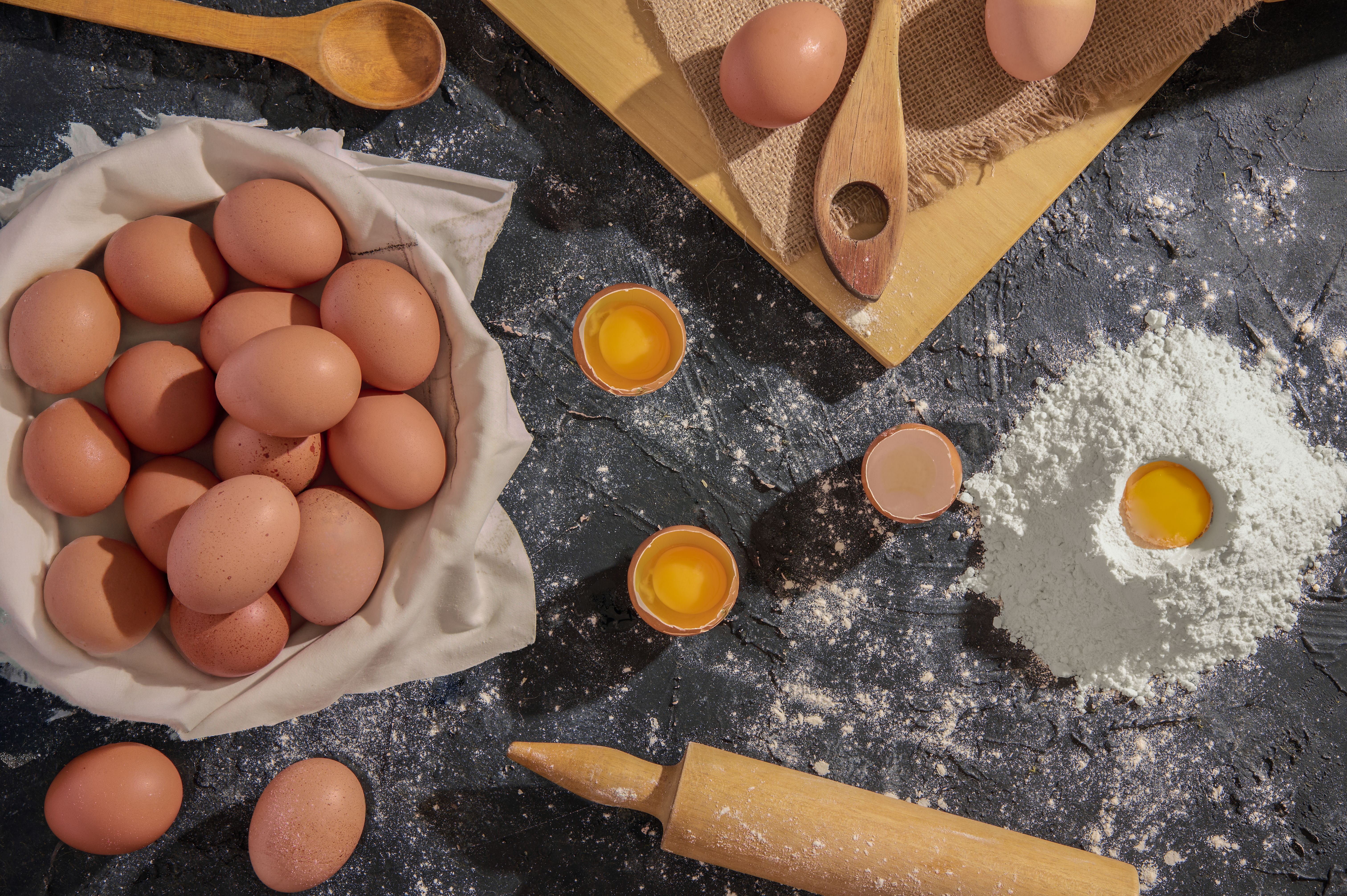 Flat lay of eggs, flour, and kitchen tools for baking preparation.