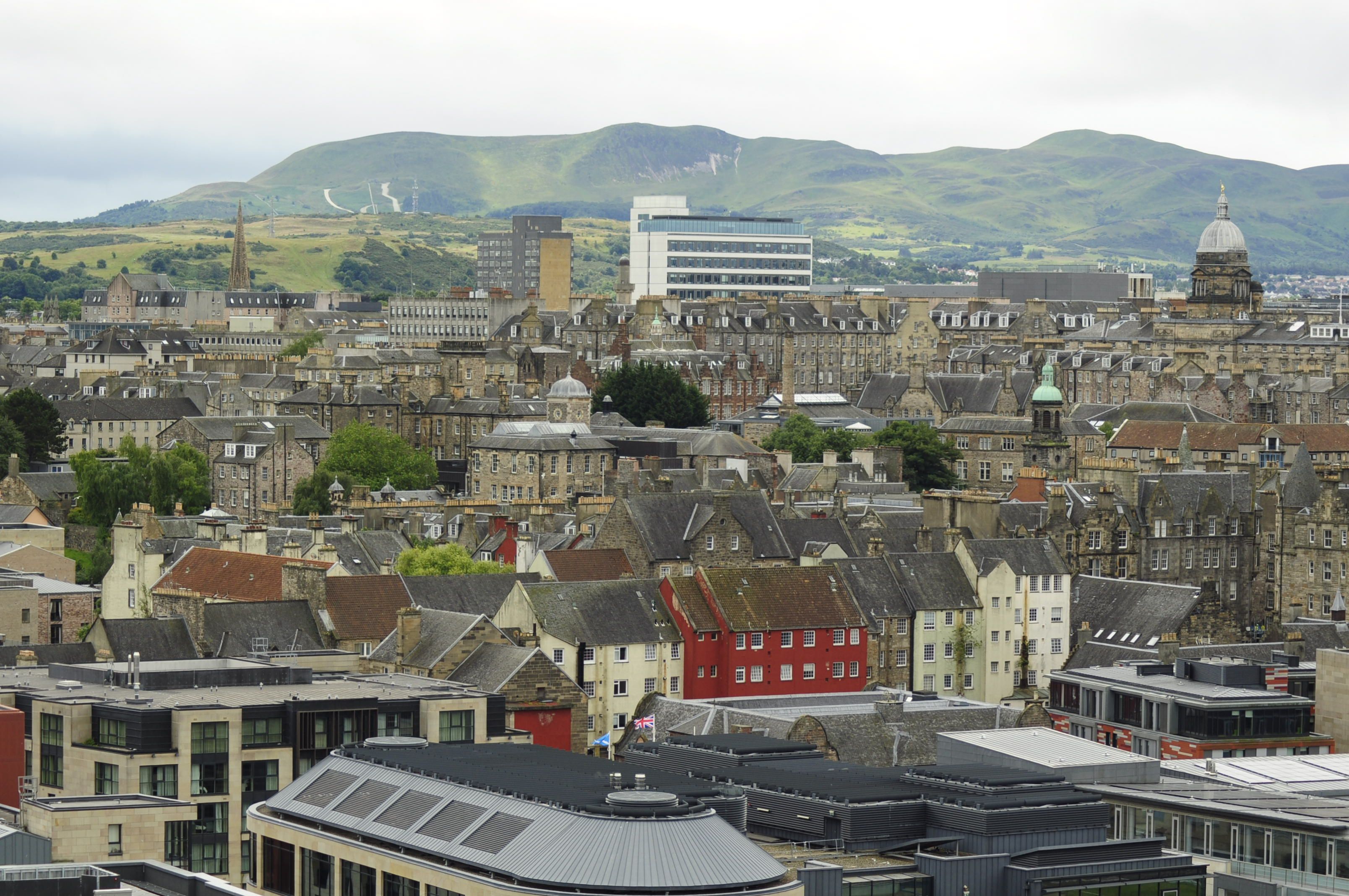 A panoramic view of the historic Edinburgh cityscape with Arthur's Seat in the background.
