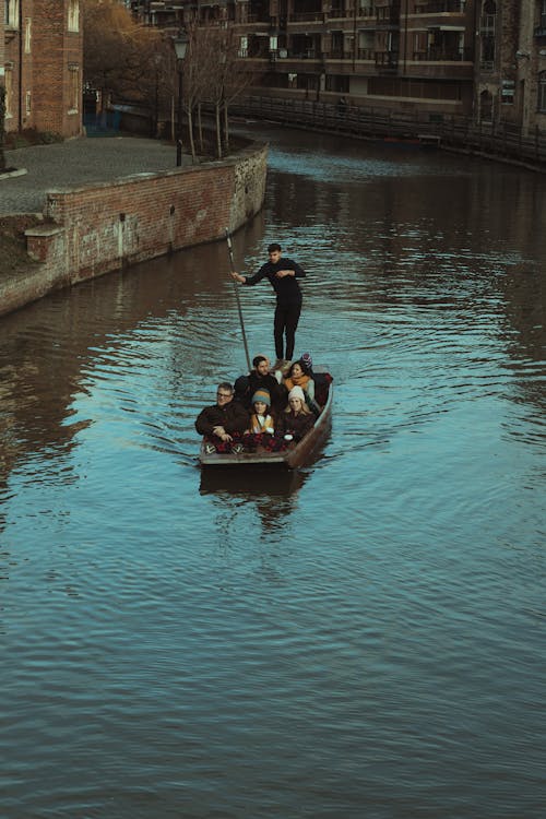 Man in Black Jacket Riding on Brown Boat on Water