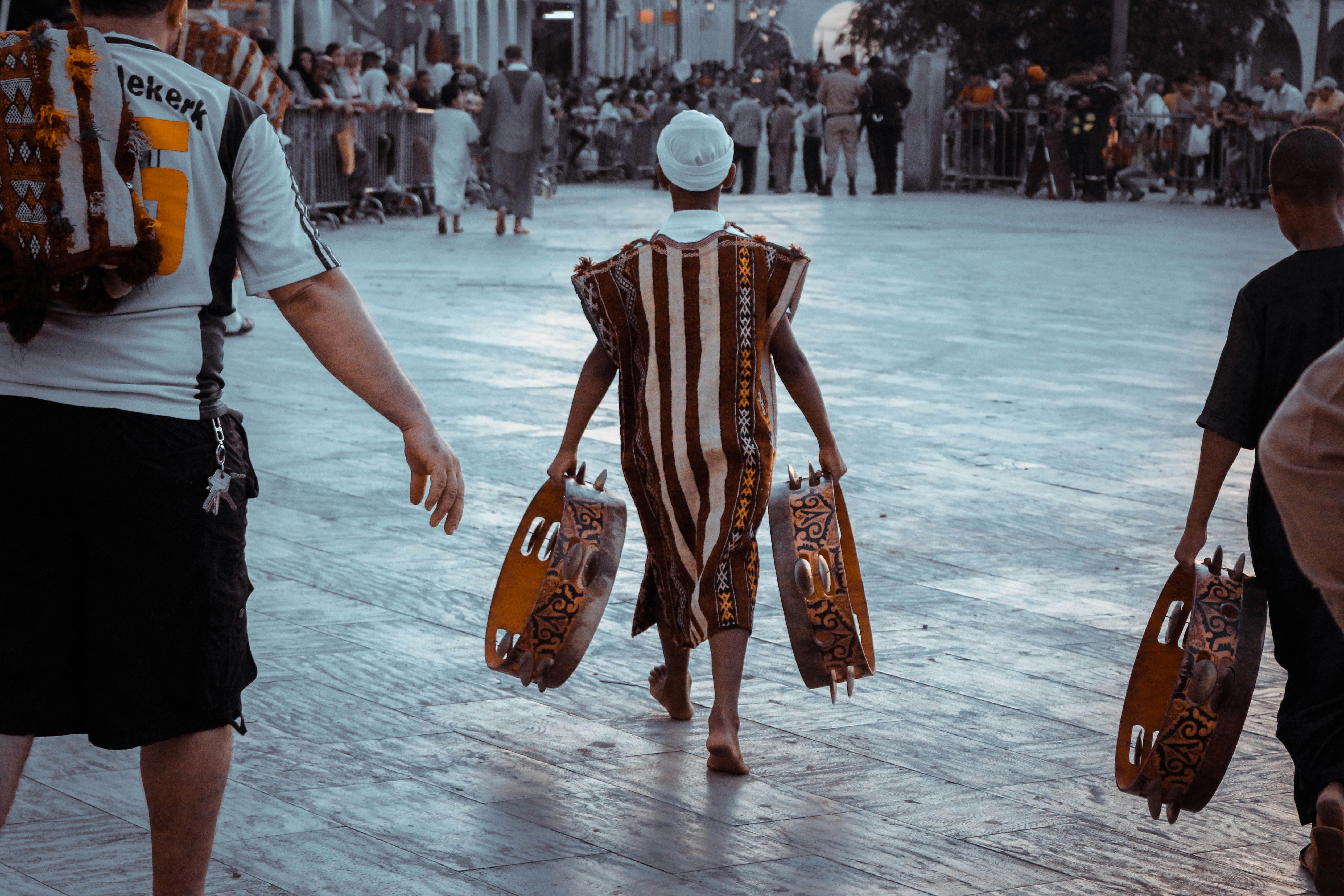 teen in african tribe clothes with tambourines on crowded square