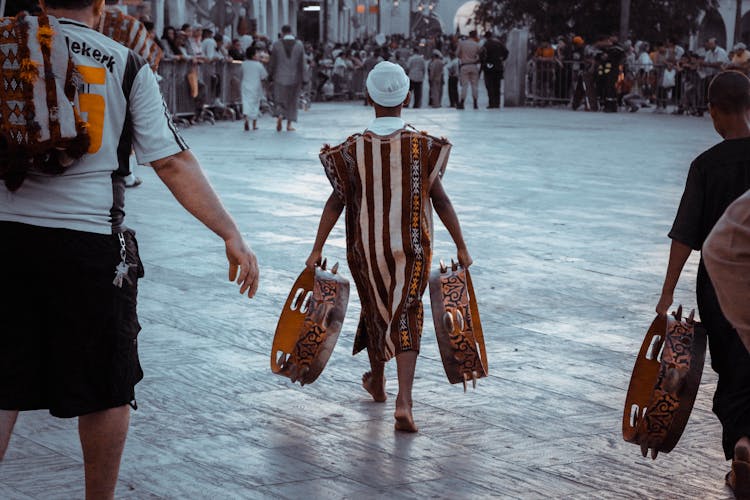 Teen In African Tribe Clothes With Tambourines On Crowded Square