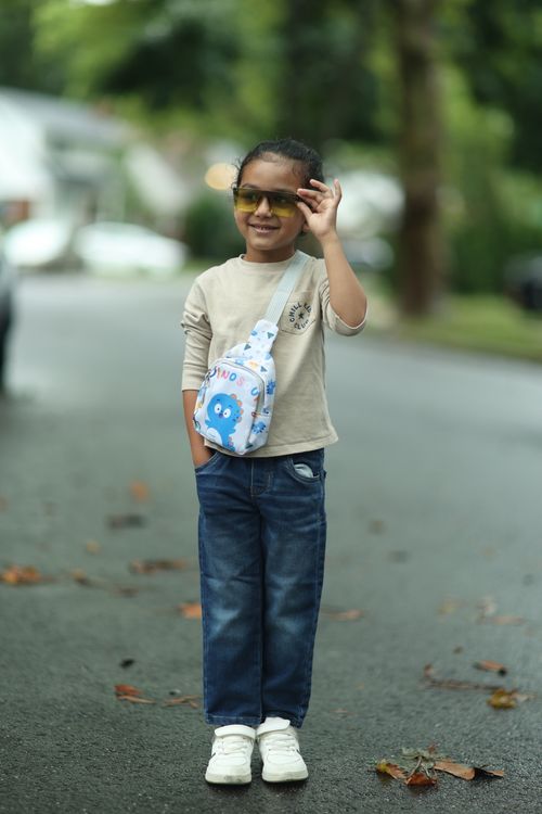 Free Smiling child with sunglasses and backpack standing on a quiet residential street. Stock Photo