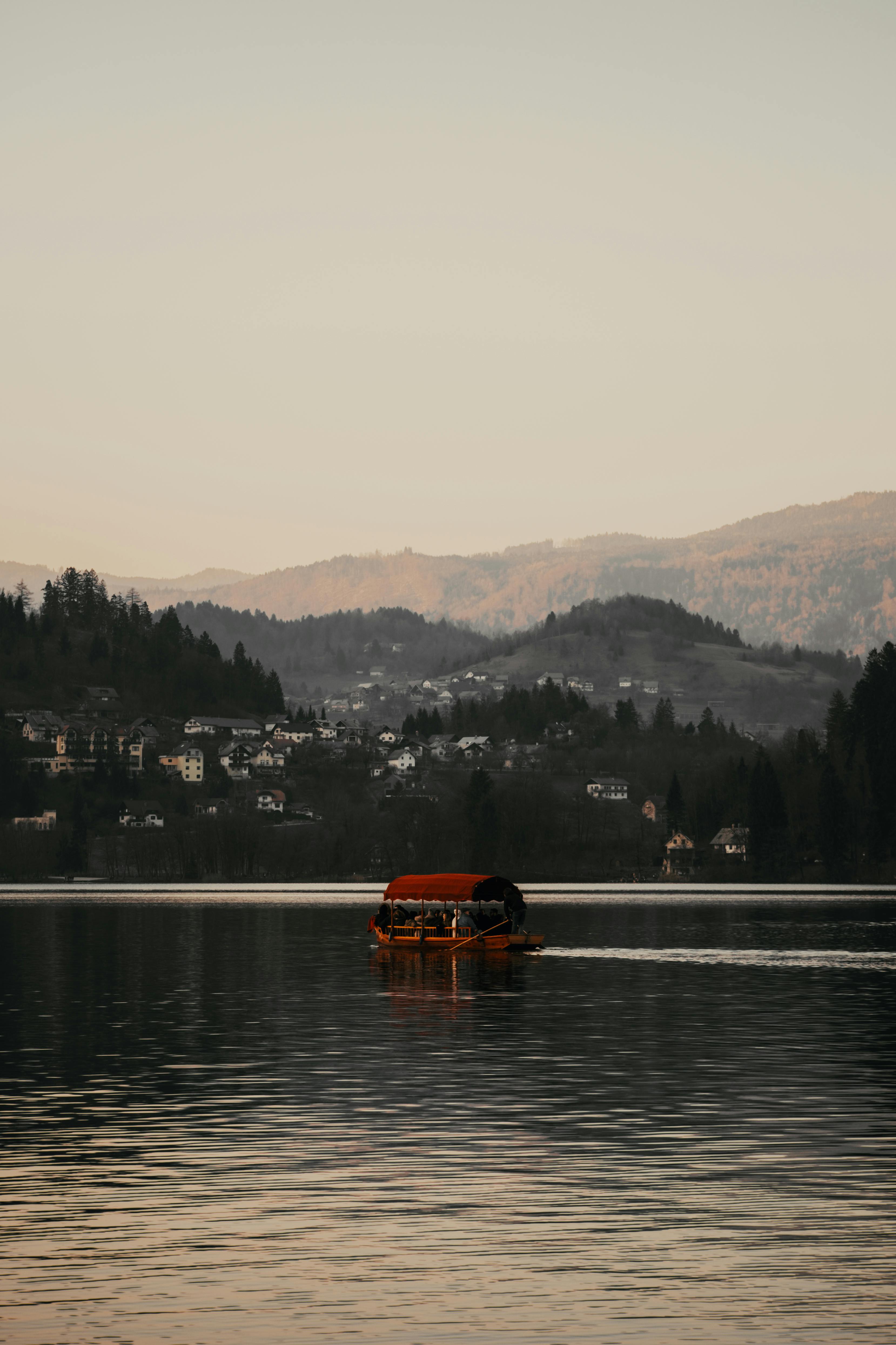 Free A tranquil boat ride on Lake Bled with a stunning backdrop of mountains and serene water at dawn. Stock Photo