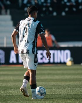 Soccer player in uniform on the field during a daytime match, preparing to kick the ball.