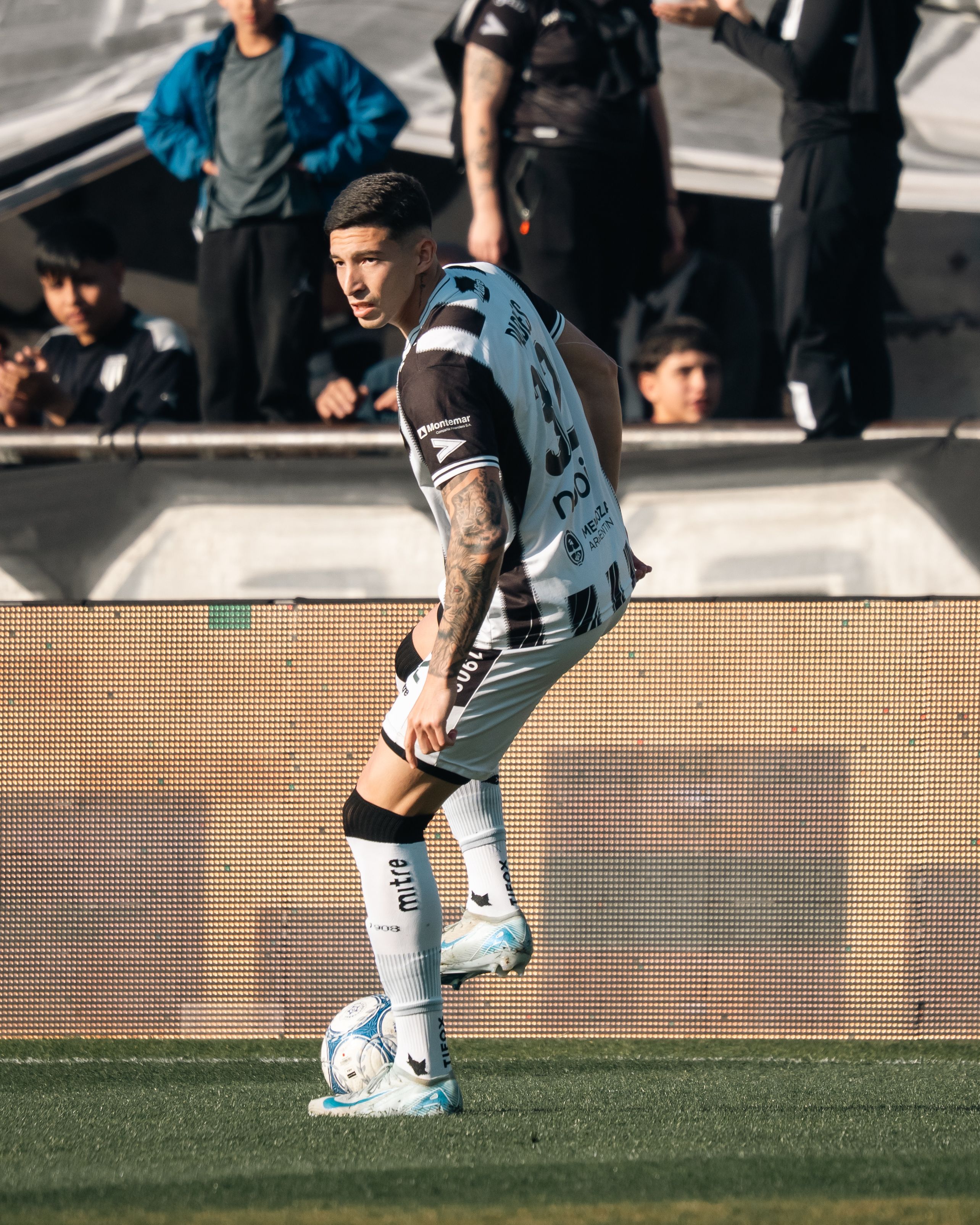 Soccer player poised to kick the ball during a match with an audience in the background.