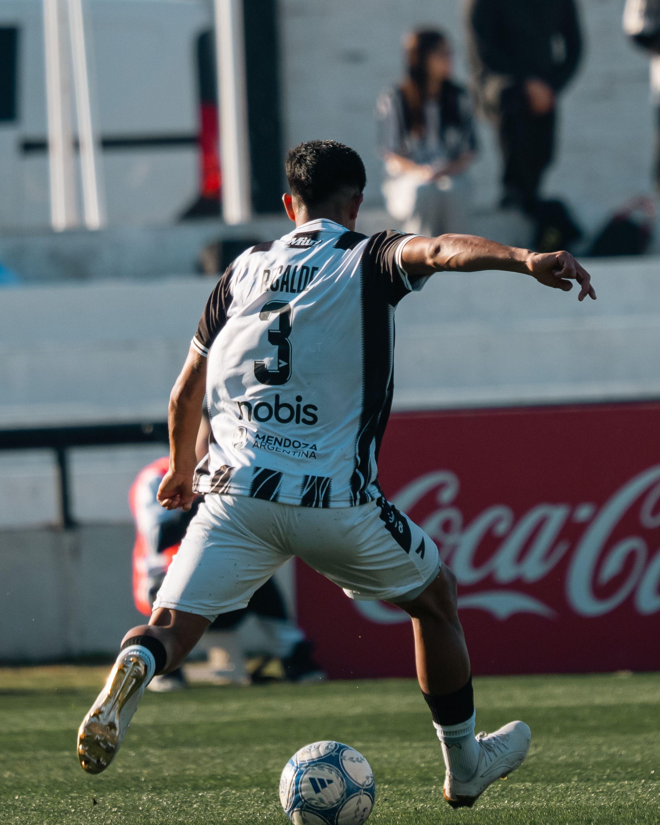 Dynamic shot of a soccer player kicking the ball on the field during a game.
